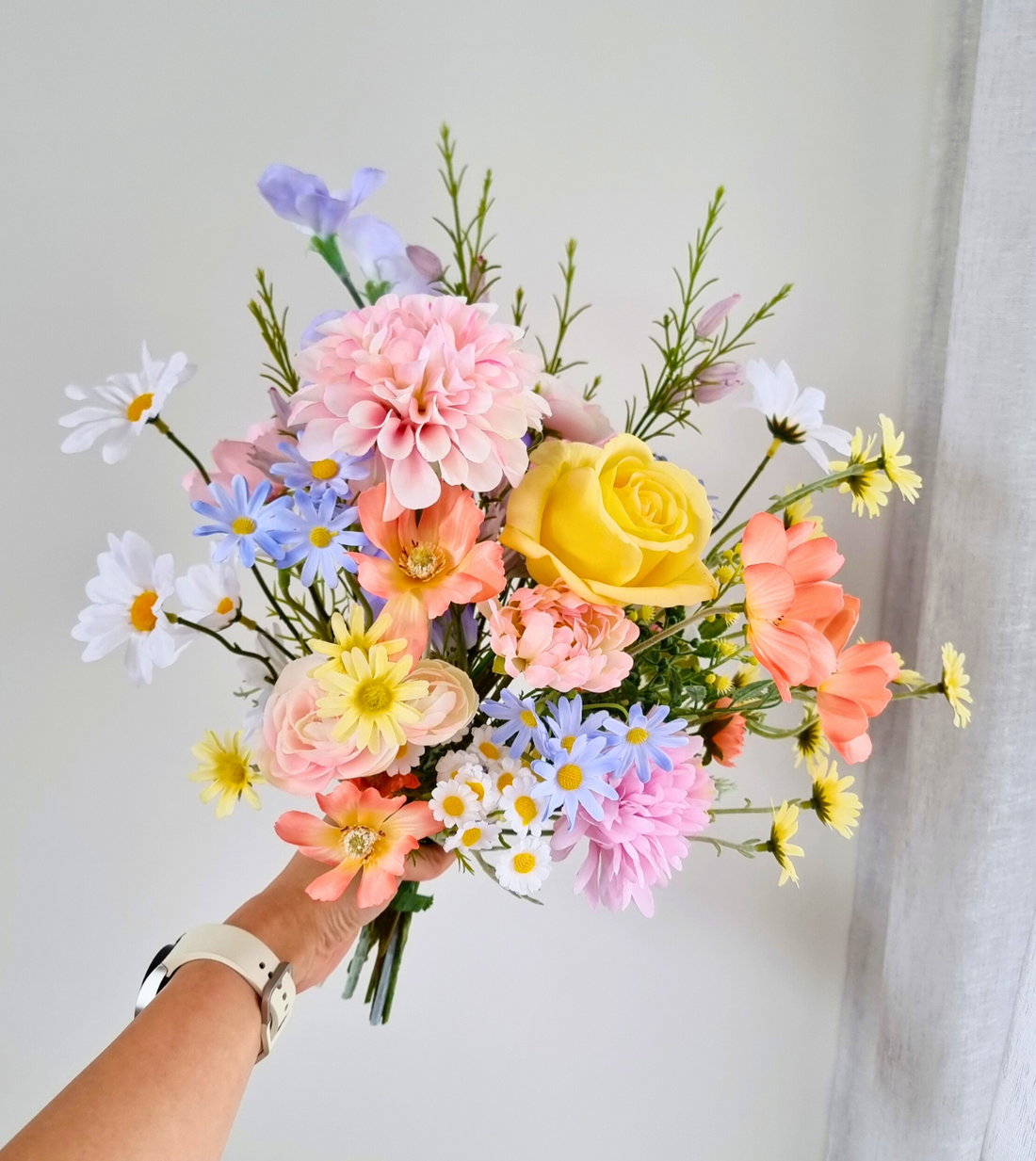A whimsical pastel bouquet of roses, daisies, and wildflowers